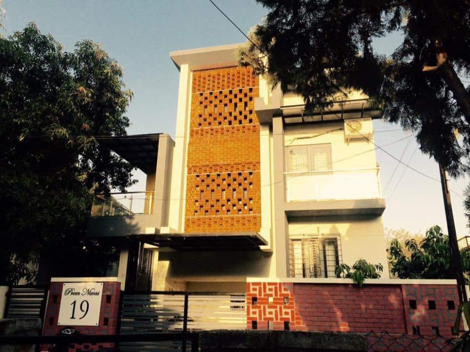 3-Storeyed-Bungalow-with-an-Exposed-Brick-Patterned-Facade-a-Compound-Wall-a-Balcony-on-one-Side-with-Glass-Railings 3 Storeyed Bungalow with an Exposed Brick Patterned Facade a Compound Wall a Balcony on one Side with Glass Railings