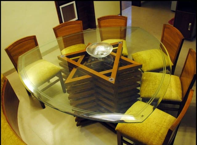 A-Leaf-Shaped-Dining-Table-with-Wooden-Pedestal-Support-Glass-top-Upholstered-Wooden-Dining-Chairs-Long-Seating-under-the-Window.-1 Swiper Content 0