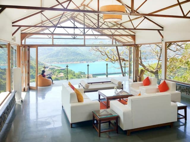 A-Living-Room-having-an-Elegant-View-of-River-Nature-surround-accommodating-White-Coloured-Square-Armed-Sofa. Swiper Content 0