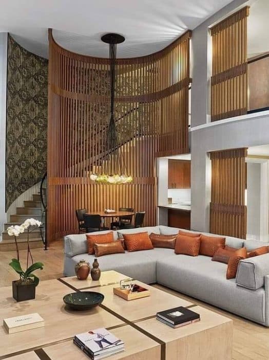 A-Luxurious-Living-Room-consist-of-a-Light-Grey-Coloured-L-Shaped-Modular-Sectional-Sofa-with-Rustic-Cushions-Large-Wooden-Center-Table-holding-Books-Artifacts-Indoor-Small-Plants-etc. Swiper Content 0