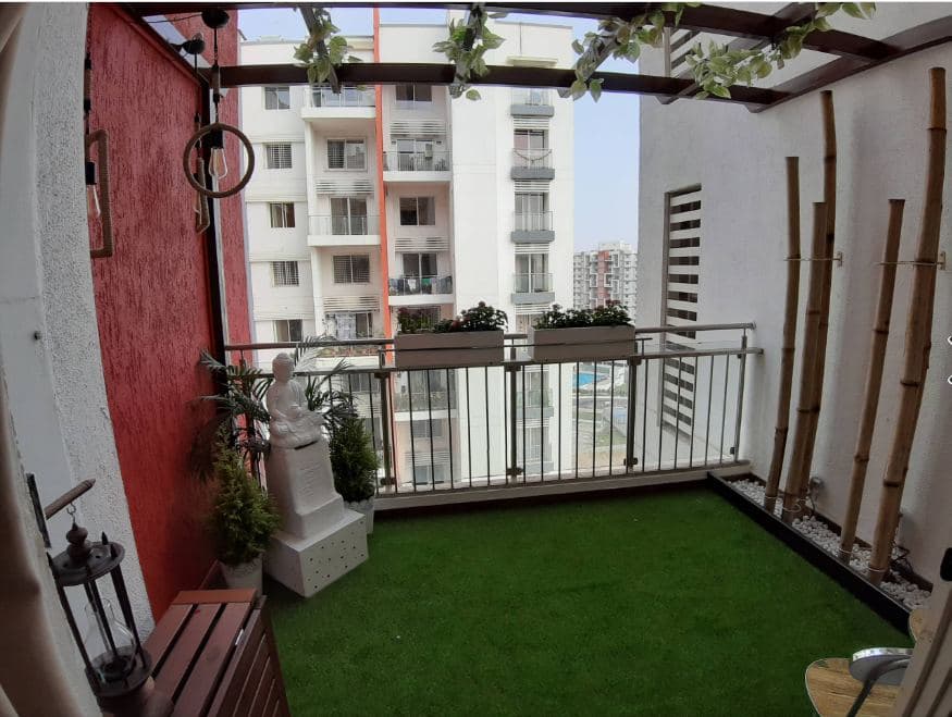 Balcony-designed-with-Artificial-Grass-Mat-on-the-Floor-with-Pedestal-Statue-of-Buddha-in-White-Bamboo-Sticks-on-one-side-over-White-Pebbles-tied-with-a-Thread-1 Balcony designed with Artificial Grass Mat on the Floor with Pedestal Statue