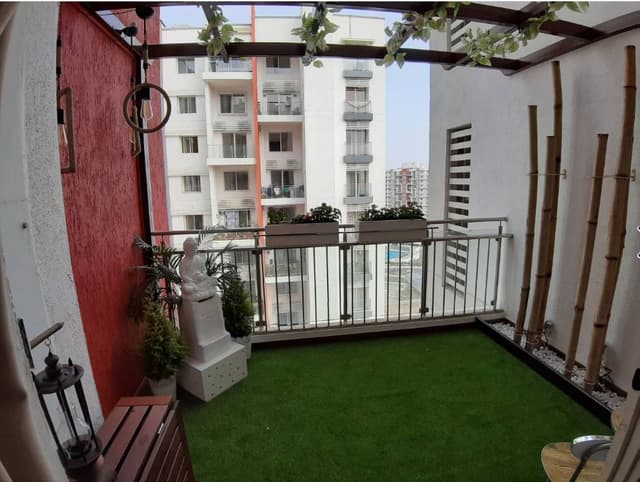 Balcony-designed-with-Artificial-Grass-Mat-on-the-Floor-with-Pedestal-Statue-of-Buddha-in-White-Bamboo-Sticks-on-one-side-over-White-Pebbles-tied-with-a-Thread-1 Balcony designed with Artificial Grass Mat on the Floor with Pedestal Statue