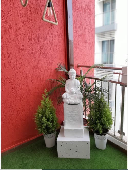 Balcony-designed-with-Artificial-Grass-Mat-on-the-Floor-with-Pedestal-Statue-of-Buddha-in-White-Bamboo-Sticks-on-one-side-over-White-Pebbles-tied-with-a-Thread-2 Balcony designed with Artificial Grass