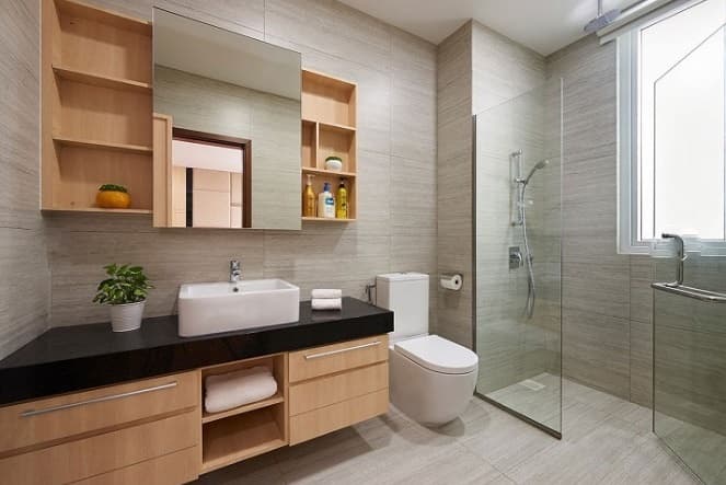 Bathroom-with-One-Colour-Tile-incorporates-Table-Top-Wash-Basin-on-Black-Counter-with-Wooden-Cabinet-including-Shelves-below-Floor-Mounted-WC-and-Shower-Area-separated-by-Glass-Partition. Design Detail Banner 0