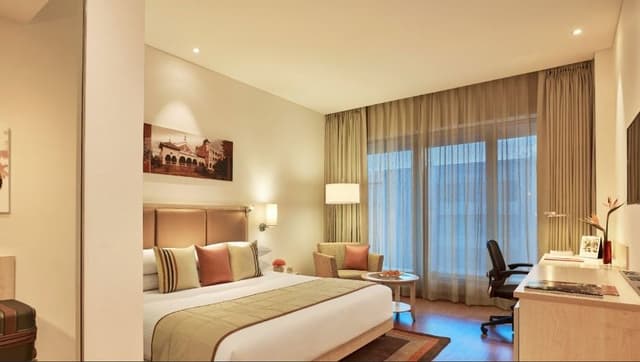 Bedroom-designed-in-Beige-Theme-with-Platform-Bed-Bed-Runner-High-Upholstered-Headboard-Side-Tables-Wooden-Working-Desk-Armchair Swiper Content 0