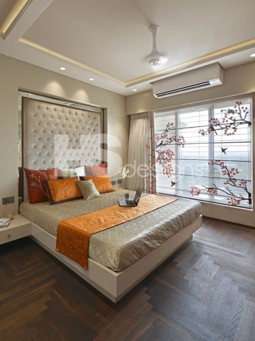Bedroom-in-the-Beige-Colour-Theme-accommodating-Wooden-Bed-attached-Side-Tables-High-Cushioned-Tufted-Headboard-highlighted-with-Spot-Lights-above-French-Windows-Wooden-Vinyl-Flooring Design Detail Banner 0
