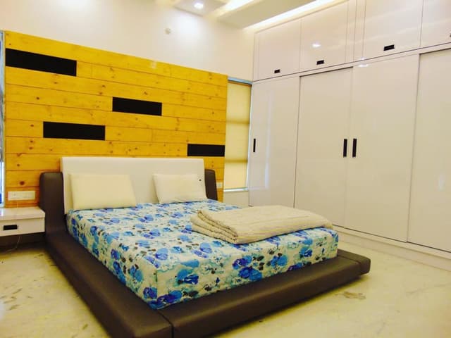 Bedroom-incorporating-Dark-Brown-Leather-Upholstered-Low-Heighted-Platform-Double-Bed-White-Leather-Upholstered-Headboard-Side-Tables-Bed-Back-Wall-with-Yellow-Polished-Wooden-Planks. Swiper Content 0