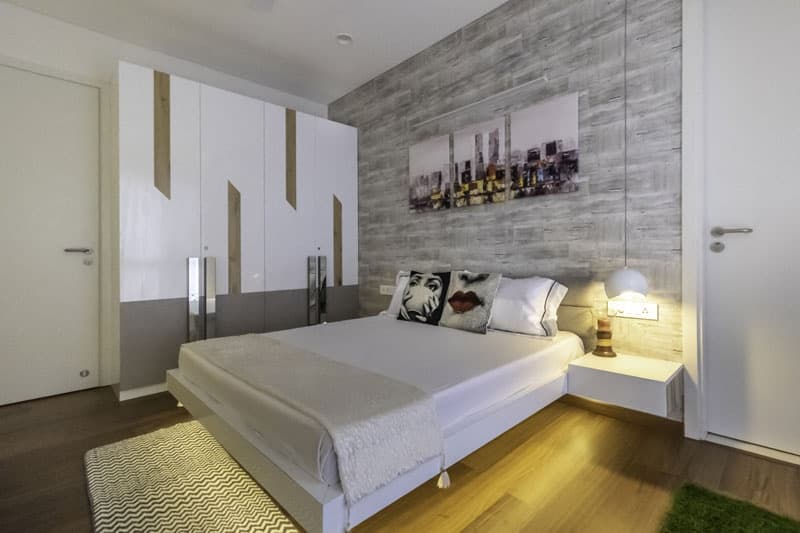 Bedroom-with-Artificial-Turf-Wooden-Flooring-comprises-of-Solid-White-Double-Bed-Side-Table-Upholstered-Headboard-3 Design Detail Banner 2