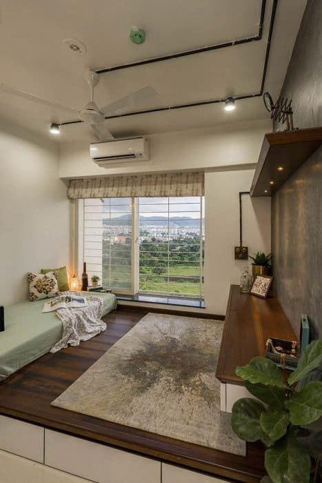 Bedroom-with-Raised-Wooden-Platform-comprising-of-Cushioned-Bed-Rug-Window-with-Roman-Roller-Blinds-Raised-Seating Swiper Content 1