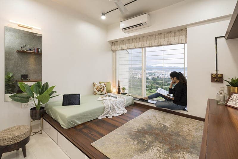 Bedroom-with-Raised-Wooden-Platform-comprising-of-Cushioned-Bed-Rug-Window-with-Roman-Roller-Blinds-Raised-Seating. Design Detail Banner 0
