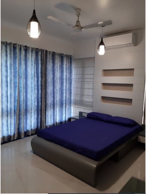 Bedroom-with-Wooden-Bed-having-Round-Edges-Attached-Side-Tables-Full-Height-Display-Shelves-on-one-Corner-Seating-Cushions-over-the-Drawers-2 Design Detail Banner 1