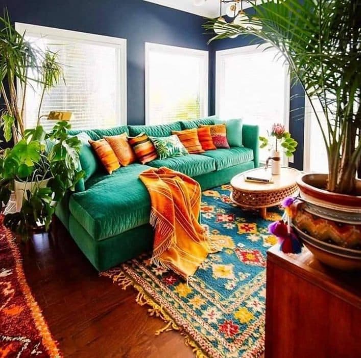 Bohemian-Styled-Living-Room-with-a-Dark-Blue-Walls-L-Shaped-Sectional-Bumper-Sofa-in-Velvet-Green-Colour-Colourful-Cushions-Throws Design Detail Banner 0
