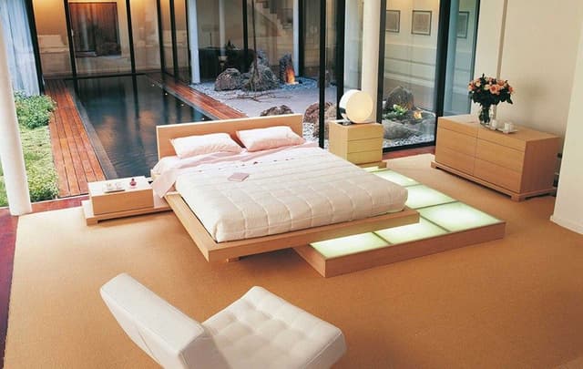 Contemporary-Bedroom-designed-with-Wooden-Bed-Side-tables-Wooden-Chest-of-Drawers-with-a-Flower-Vase-on-it-Sofa-Chair Swiper Content 0