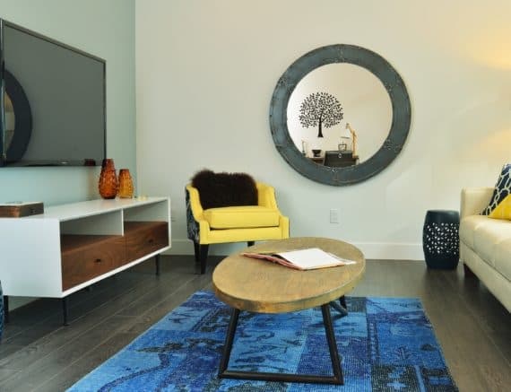 Designer-Low-heighted-Yellow-Upholstered-Armchair-Accent-Chair-with-a-Black-Cushion-in-a-Small-Minimalistic-Styled-Living-Room-with-a-Wooden-Coffee-Table Design Detail Banner 0