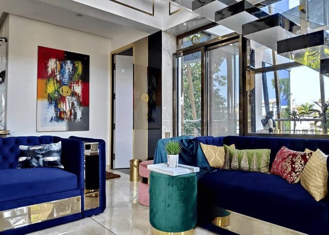 Double-Heighted-Luxurious-Open-Plan-Living-Room-with-Glass-Facade-incorporates-Royal-Blue-Sofa-Set-with-Sofa-Cum-Bed-facility Swiper Content 2