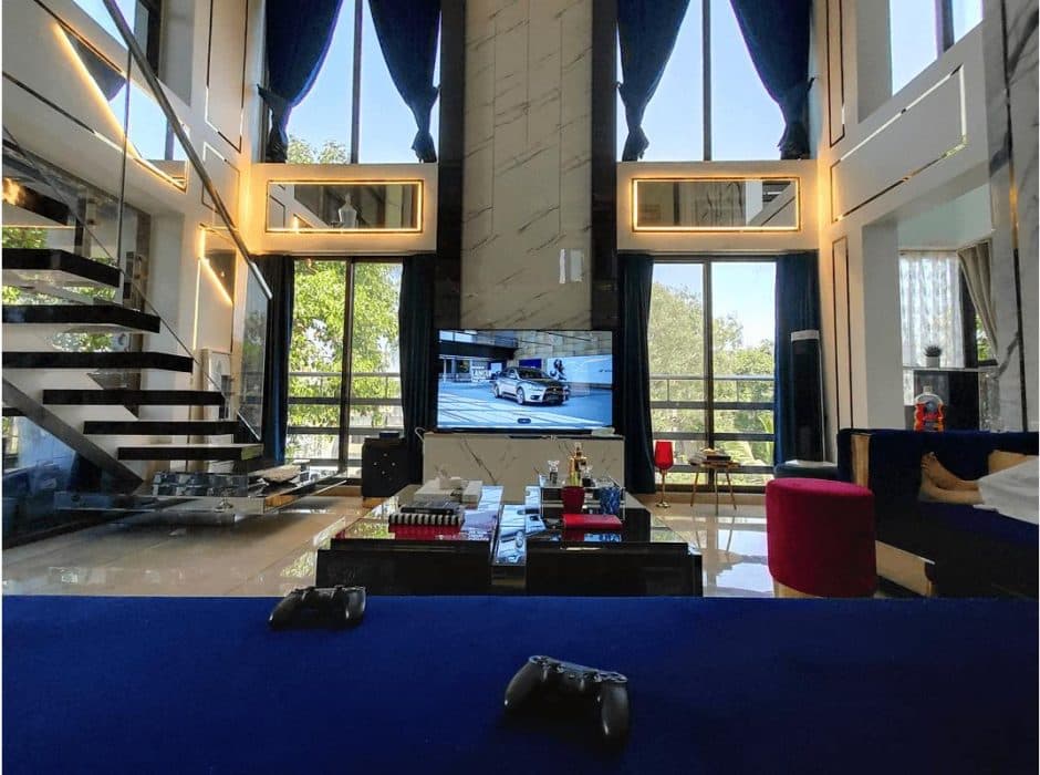 Double-Heighted-Luxurious-Open-Plan-Living-Room-with-Glass-Facade-incorporates-Royal-Blue-Sofa-Set-with-Sofa-Cum-Bed-facility.-1 Design Detail Banner 1