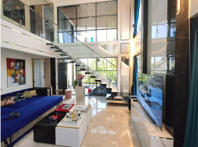 Double-Heighted-Luxurious-Open-Plan-Living-Room-with-Glass-Facade-incorporates-Royal-Blue-Sofa-Set-with-Sofa-Cum-Bed-facility. Swiper Content 0