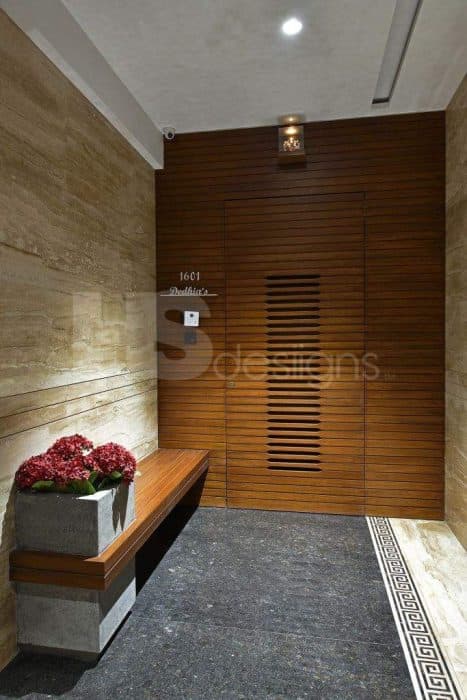 Entry-Door-made-up-of-Wooden-Battens-with-Voids-in-the-Center-of-a-Door.-It-is-surrounded-by-Wooden-Battens-Wall-Panelling-on-3-Sides.-Its-adjacent-Walls-have-Stone-Tile-Cladding. Design Detail Banner 0