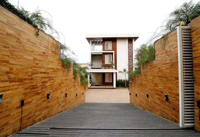 Exterior-View-of-Contemporary-Styled-White-Brown-Themed-G1-Storey-Bungalow-highlighted-with-Backlit-Jali-Wall-1 Swiper Content 0