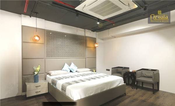 Industrial-Style-Bedroom-with-Exposed-Dark-Ceiling-with-Pipes-Track-Lights-Pendant-Lights-Wooden-Flooring-Upholstered-Double-Bed-Wall-Mounted-Side-Tables-with-Drawer Swiper Content 0