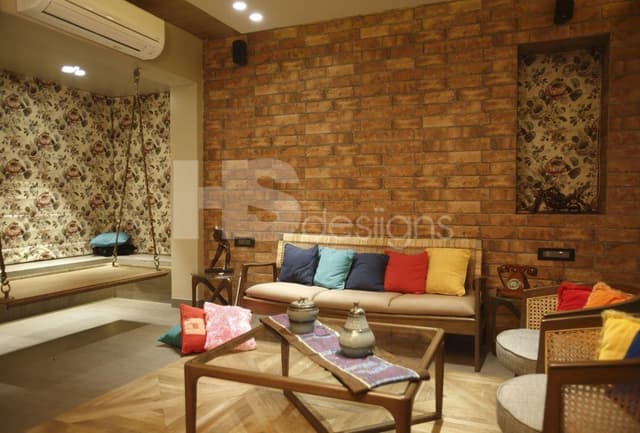 Living-Room-in-Rustic-Theme-accommodating-Wooden-cum-Wicker-Sofa-Set-with-Colourful-Cushions-Wooden-Coffee-Table-with-Glass-top-Half-Round-Chairs-Projector-Built-in-Wall-Shelves Swiper Content 0