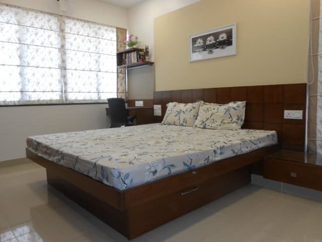 Minimalistic-Small-Bedroom-accommodates-Wooden-Bed-with-Storage-Wooden-Headboard-attached-Side-Table-on-one-side-another-side-as-a-Working-Desk Swiper Content 0