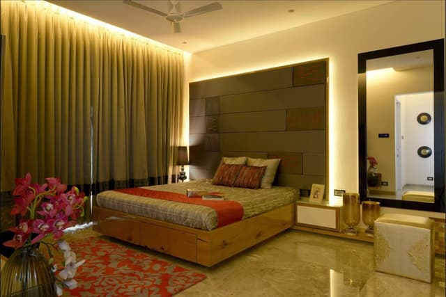 Modern-Bedroom-accommodating-Wooden-Bed-Side-Tables-with-Table-Lamp-placed-on-it-Textured-Backwall-with-Cove-Lighting-behind Swiper Content 0
