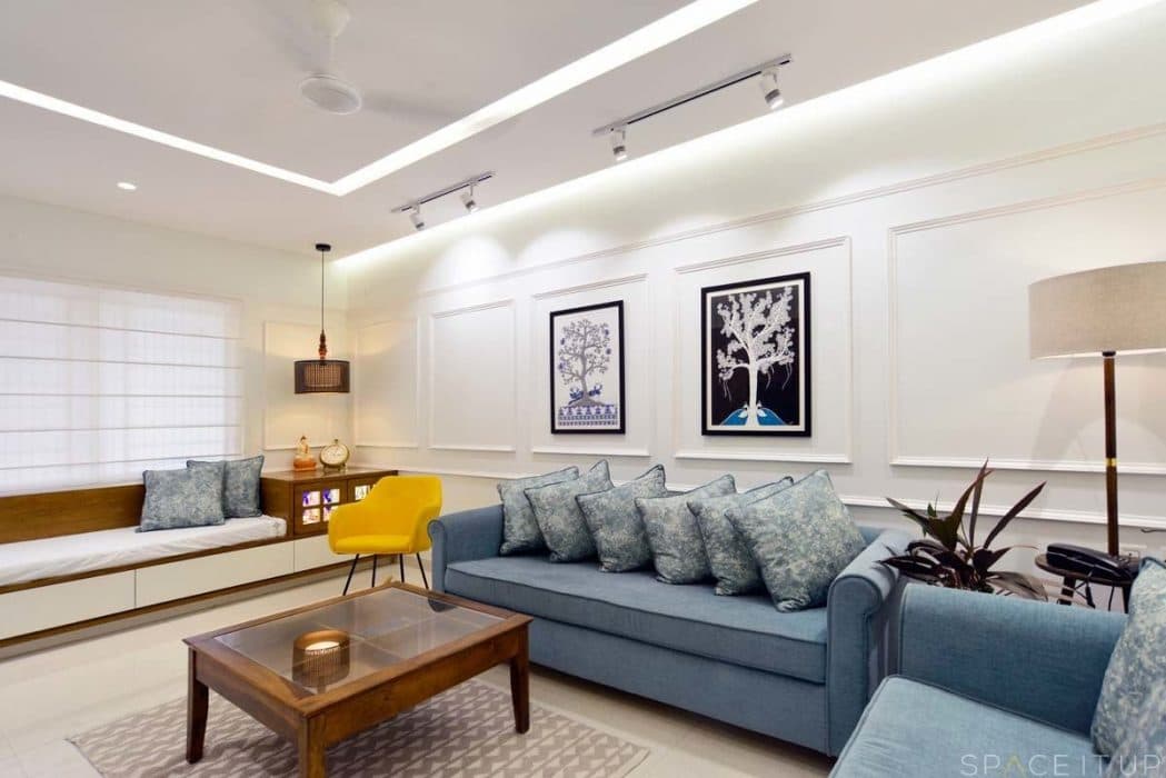 Modern-Living-Room-designed-with-Blue-Coloured-Roll-Arm-Sofa-Set-Wooden-Glass-Top-Coffee-Table-placed-on-a-Rug-Corner-Side-Table-with-Table-Lamp-Wall-mounted-T.V.-Unit-5 Design Detail Banner 4