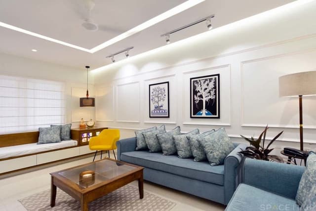 Modern-Living-Room-designed-with-Blue-Coloured-Roll-Arm-Sofa-Set-Wooden-Glass-Top-Coffee-Table-placed-on-a-Rug-Corner-Side-Table-with-Table-Lamp-Wall-mounted-T.V.-Unit-5 Swiper Content 4