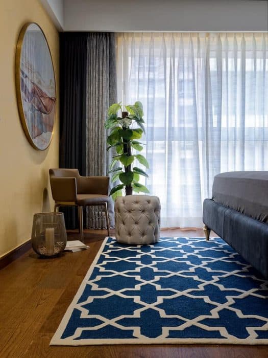 Modern-Low-Back-Chair-with-Metal-Frame-a-White-Tufted-Pouf-in-a-Corner-of-Bedroom-complemented-with-Indoor-Plant-Metallic-Candle-Big-Vase-Holder Design Detail Banner 0