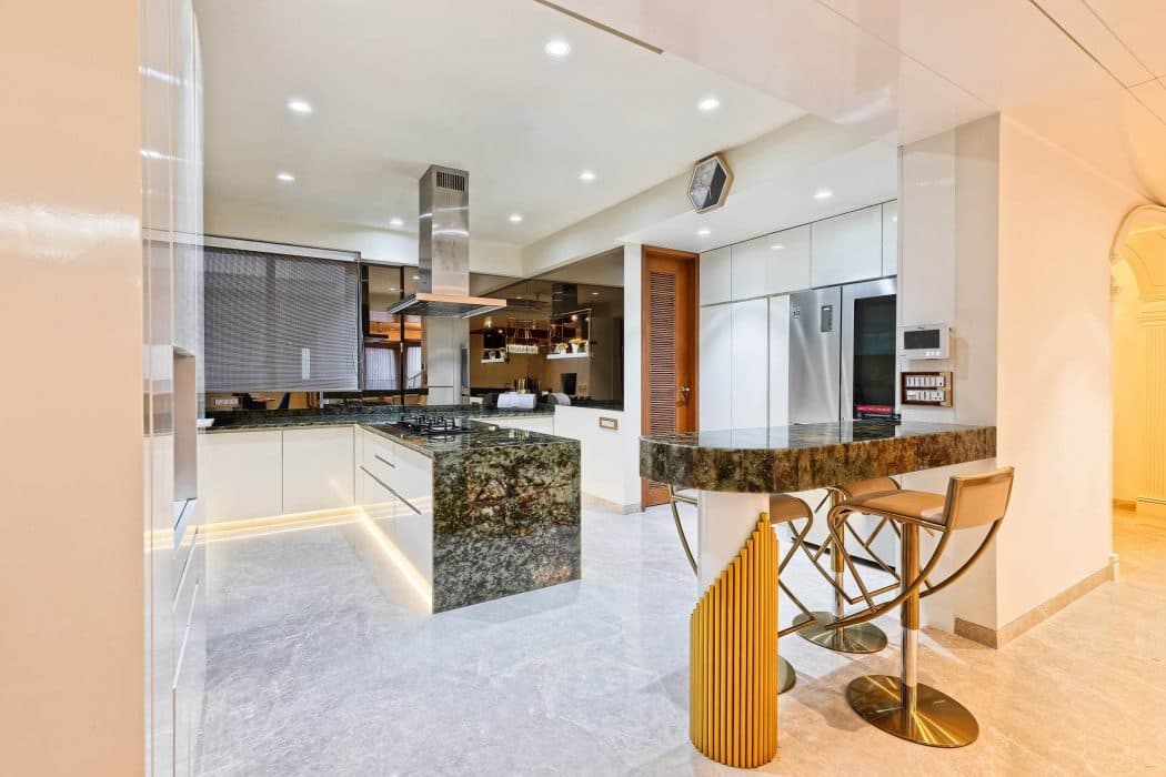 Modular-Kitchen-with-Granite-Countertop-Breakfast-Counter-on-one-corner-of-the-Kitchen-with-Bar-Chairs-Lighting-below-the-Lower-Cabinets-Island-Kitchen-Chimney Design Detail Banner 1