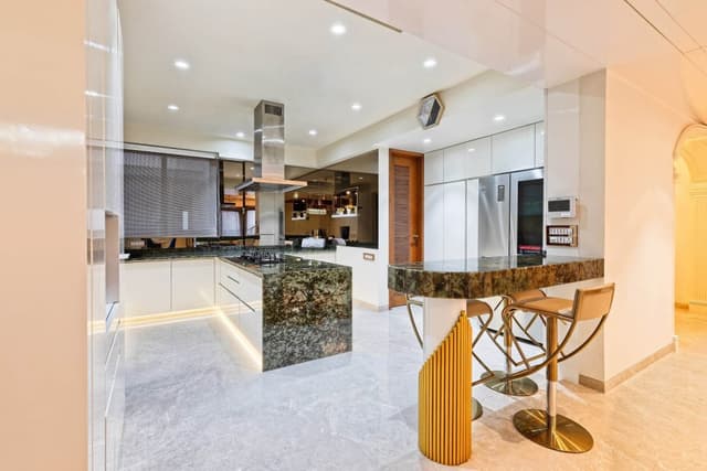 Modular-Kitchen-with-Granite-Countertop-Breakfast-Counter-on-one-corner-of-the-Kitchen-with-Bar-Chairs-Lighting-below-the-Lower-Cabinets-Island-Kitchen-Chimney Swiper Content 1