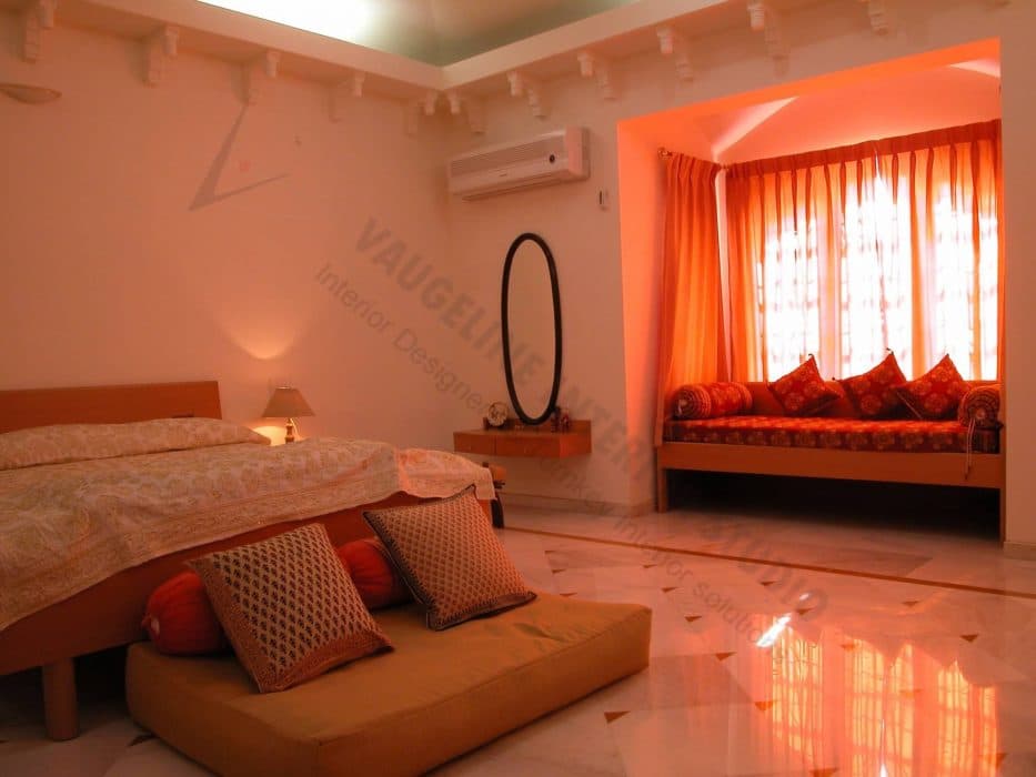 Orange-Themed-Bedroom-incorporates-Double-Bed-with-Wooden-Legs-Cushioned-Floor-Seating-at-End-of-Bed-with-Cushions-Side-Table-with-Table-Lamp Design Detail Banner 0
