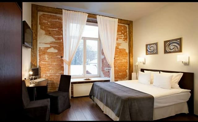 Rustic-Styled-Bedroom-with-an-Exposed-Brick-Featured-Wall-Window-in-a-Center-with-a-Center-Window-Seating-covered-with-Sheer-Curtains Swiper Content 0