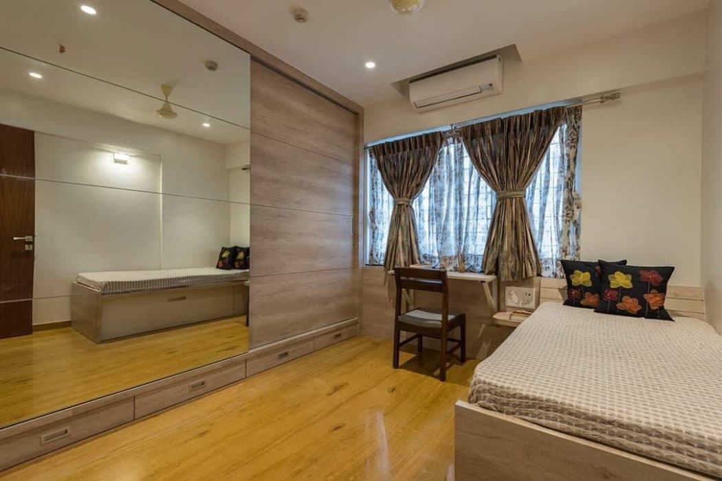 Single-Bedroom-with-Small-Side-Table-is-Thoughtfully-Place-in-this-Compact-Bedroom.-Wardrobe-on-the-Opposite-Side-having-Drawers-at-the-Bottom-having-Sliding-Doors. Design Detail Banner 0