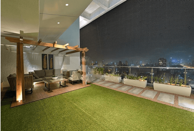 Spacious-Balcony-with-Glass-Railing-and-Stainless-Steel-Handrail-incorporates-Artificial-Turf-Flooring-Stone-Flooring-Ceiling-with-Recessed-Lights-highlighted-with-Grooves. Swiper Content 0