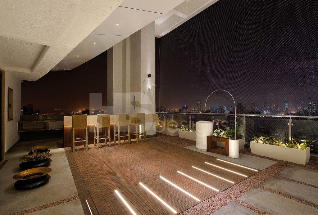 Spacious-Balcony-with-Glass-Railing-and-Stainless-Steel-Handrail-incorporates-Bar-Table-with-Under-Counter-Lights-Bar-Chairs-Wooden-Stone-and-Weatherproof-Pebble-Epoxy-Flooring. Design Detail Banner 0