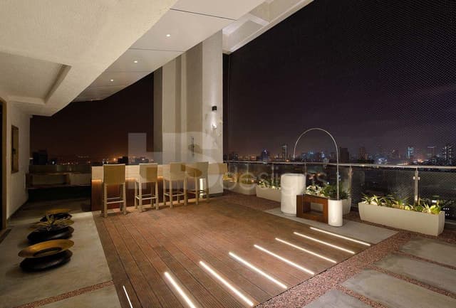 Spacious-Balcony-with-Glass-Railing-and-Stainless-Steel-Handrail-incorporates-Bar-Table-with-Under-Counter-Lights-Bar-Chairs-Wooden-Stone-and-Weatherproof-Pebble-Epoxy-Flooring. Swiper Content 0