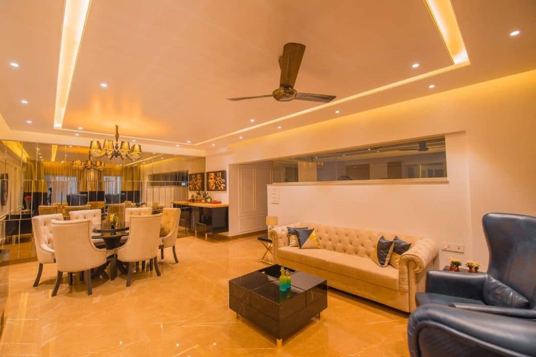 This-Luxurious-Living-Room-having-a-Cream-Chesterfield-Sofa-two-High-Wingback-Blue-chairs.-Black-Glossy-Cubicle-Center-Table-with-the-Storage-is-Functionally-Supporting-the-Seating-Area.-1 Design Detail Banner 0