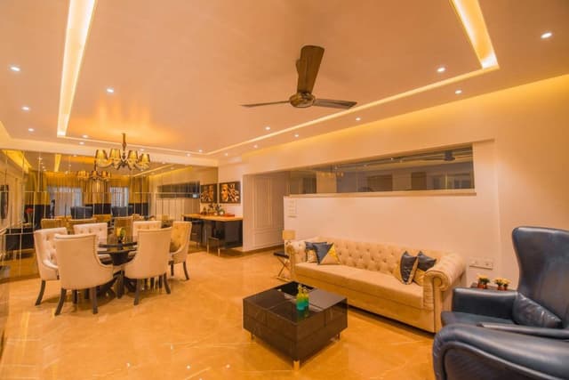 This-Luxurious-Living-Room-having-a-Cream-Chesterfield-Sofa-two-High-Wingback-Blue-chairs.-Black-Glossy-Cubicle-Center-Table-with-the-Storage-is-Functionally-Supporting-the-Seating-Area.-1 Swiper Content 0