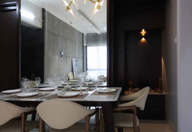 A dark frame marble topped dining table with elegant glassware and dining chairs having crème colour covering. A dark frame marble topped dining table with elegant glassware and dining chairs having crème colour covering.