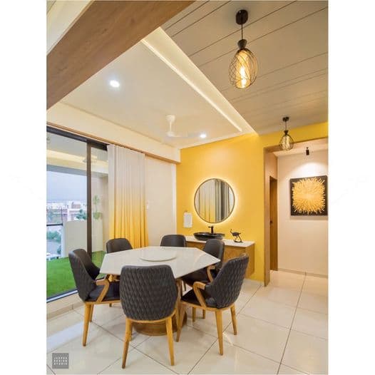 A minimalist dining area with a yellow wall and round mirror with side lights A minimalist dining area with a yellow wall and round mirror with side lights