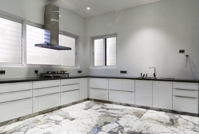 L-Shaped White Kitchen Consists of Black Granite Counter Top with Gas Stove, Chimney & Built-In Sink L-Shaped White Kitchen Consists of Black Granite Counter Top with Gas Stove, Chimney & Built-In Sink