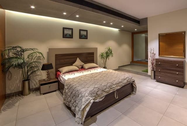 The Beige & Brown themed Bedroom consists of Rectangular Wooden Bed with Brown Backrest & Wooden Side Table The Beige & Brown themed Bedroom consists of Rectangular Wooden Bed with Brown Backrest & Wooden Side Table