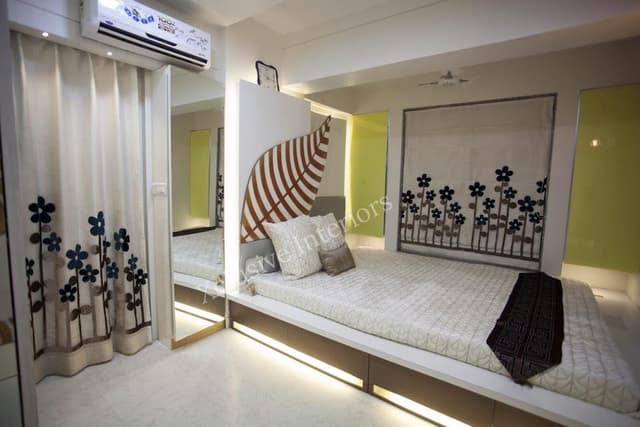 A Single Rectangular Wooden Bed having cushioned backrest is nicely placed on one side of the Bedroom A Single Rectangular Wooden Bed having cushioned backrest is nicely placed on one side of the Bedroom