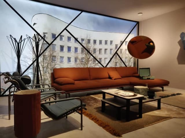The Living Room with a Full Height Glass Facade in an Inclined Line Pattern Frame has Brick Red Sectional Sofa with Metal Legs The Living Room with a Full Height Glass Facade in an Inclined Line Pattern Frame has Brick Red Sectional Sofa with Metal Legs